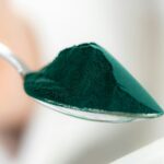 Spoon filled with nutrient-rich spirulina, showcasing its vibrant color and health benefits