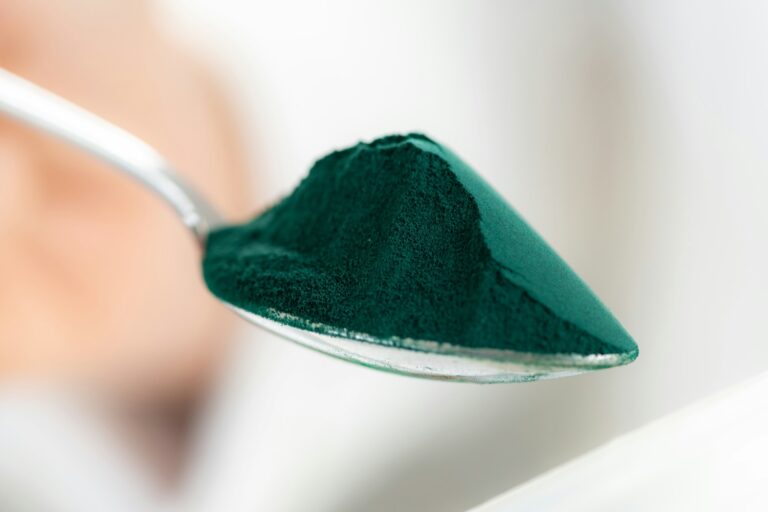 Spoon filled with nutrient-rich spirulina, showcasing its vibrant color and health benefits